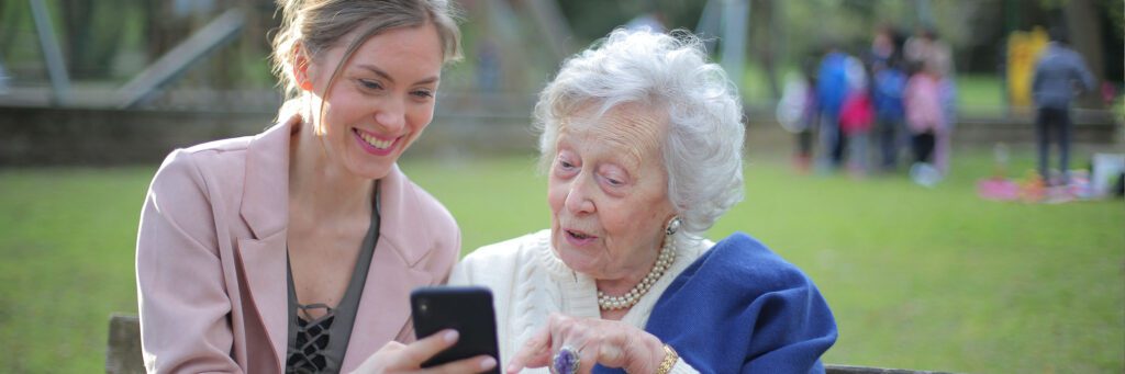 A woman and an old lady looking at a phone.